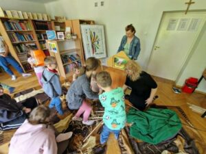 Dzieci podchodzą do drewnianej skrzynki teatrzyku kamiszibaj