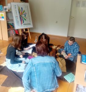Pięcioro uczniów siedzi na podłodze i czyta książki.